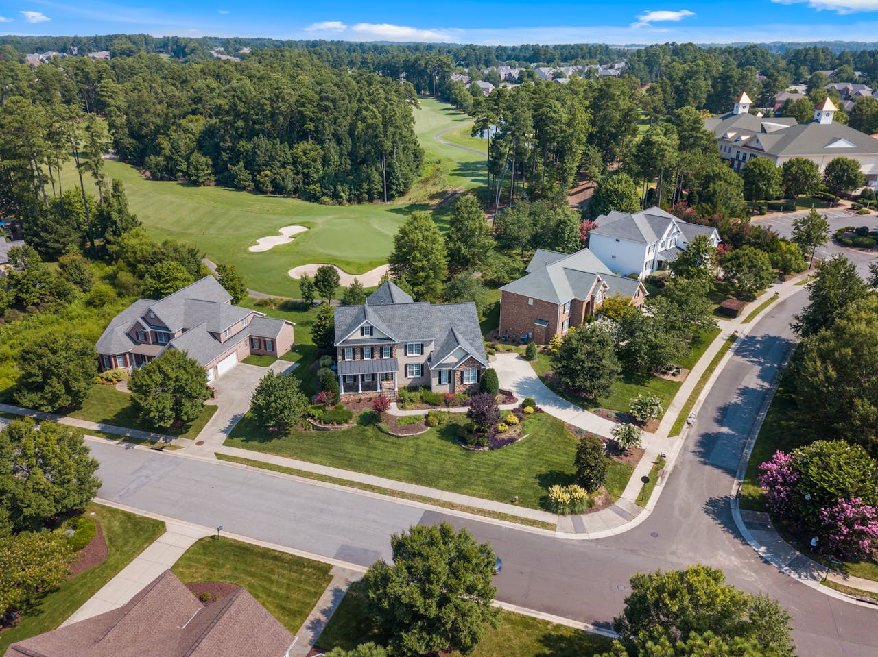 Aerial view of suburban neighborhood with lush greenery and golf course in Raleigh, NC.